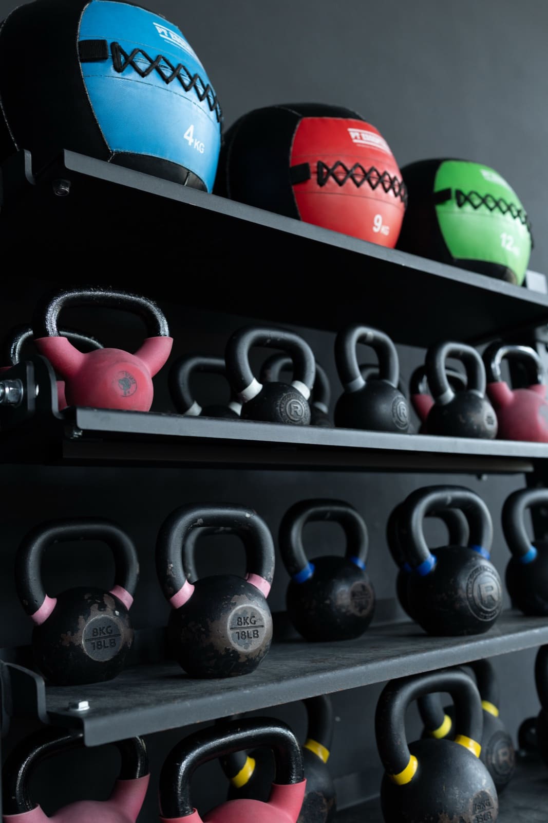 Rekken met kettlebells en gekleurde medicine balls tegen de wand bij Body Matrix Rotterdam